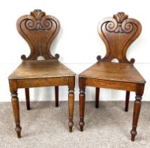 A pair of 19th century oak hall chairs, with scroll carved backs, solid seats and turned front