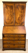 A George III mahogany bureau bookcase, the moulded cornice over two panelled doors, opening to