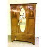 An Edwardian mahogany single door wardrobe with oval mirrored door