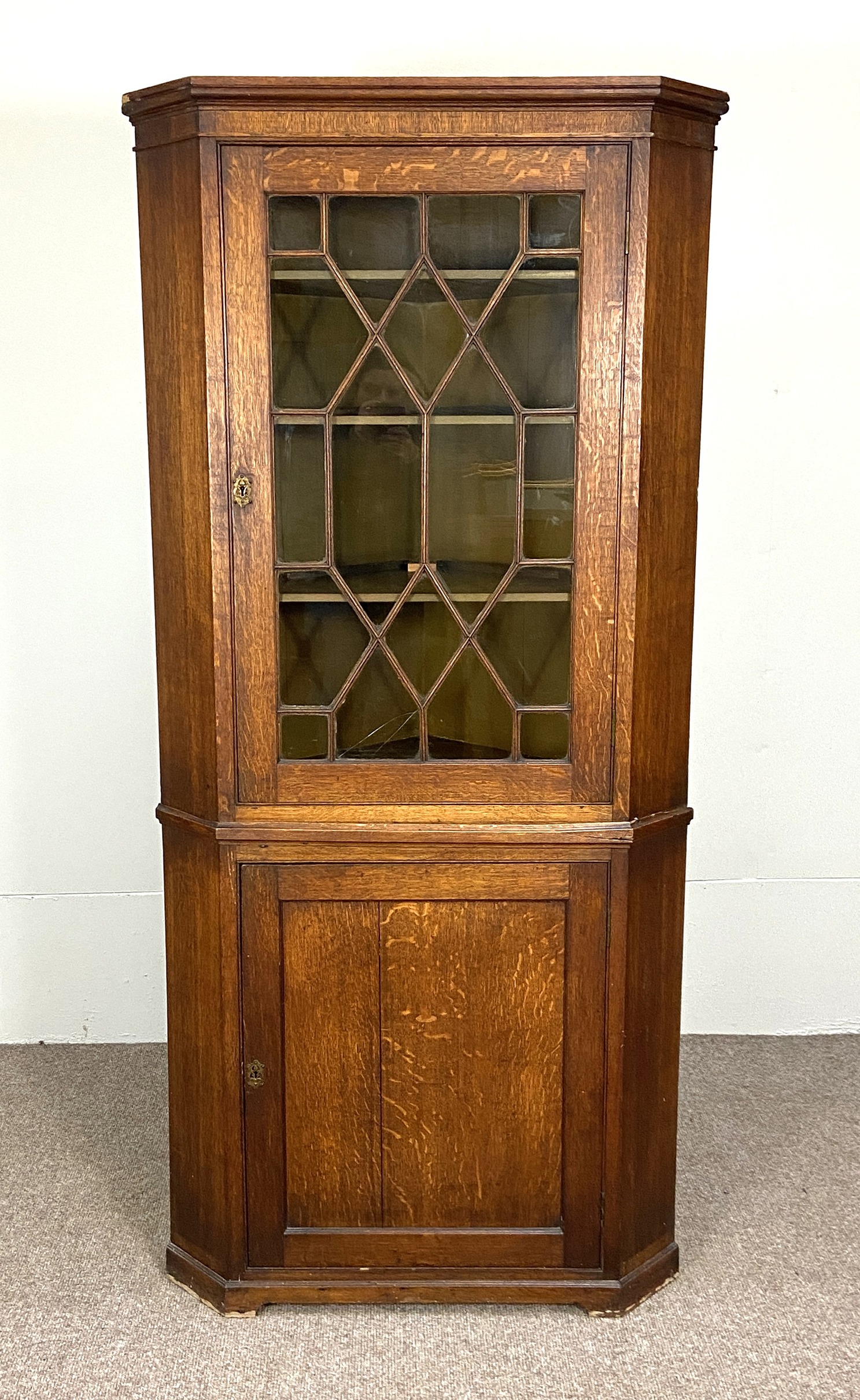 A large George III provincial oak floor standing corner cabinet, with canted sides, a single