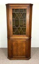 A large George III provincial oak floor standing corner cabinet, with canted sides, a single