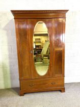 An Edwardian mahogany inlaid wardrobe, with oval mirrored door and single long drawer, 212cm high,