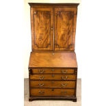 A George III mahogany bureau bookcase, the moulded cornice over two panelled doors, opening to