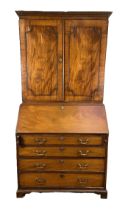 A George III mahogany bureau bookcase, the moulded cornice over two panelled doors, opening to