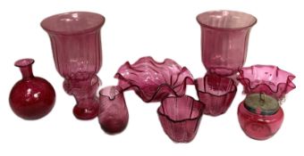 A collection of cranberry glass, including two storm lantern style vases, a pair of lobed small