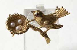 A 9 carat gold brooch of a bird beside it’s nest, hallmarked, the nest containing three small