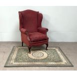 A vintage wing backed armchair, with claret upholstery; also a modern decorative rug (2)