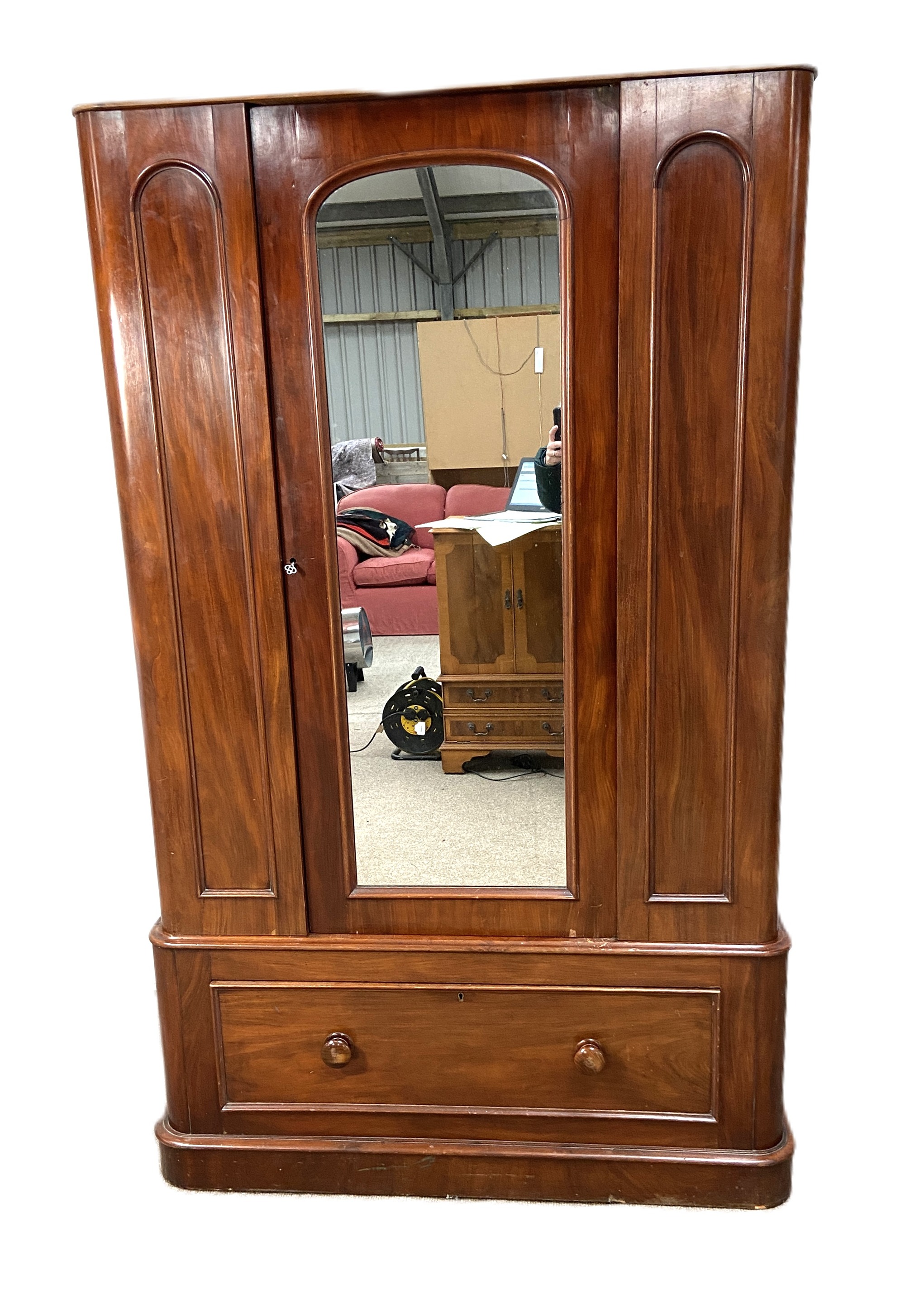 A Victorian mahogany single warbrobe, with mirrored arched door over a long drawer. (lacks