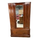 A Victorian mahogany single warbrobe, with mirrored arched door over a long drawer. (lacks