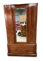 A Victorian mahogany single warbrobe, with mirrored arched door over a long drawer. (lacks