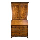 A George III mahogany bureau bookcase, the moulded cornice over two panelled doors, opening to