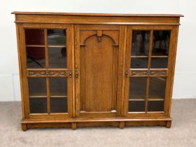 A vintage oak china cabinet, with a central arch moulded door and flanked by two glazed doors,