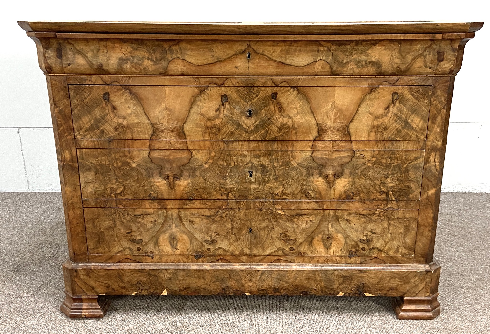 A Biedermeier walnut veneered commode, 19th century, with an ogee moulded frieze drawer over three