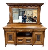 A late Victorian oak sideboard, with mirrored back over three concave fronted frieze drawers over