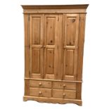 A pine three door compactum wardrobe, late 20th century, with hanging space, linen shelves and