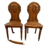 A pair of Victorian oak hall chairs, with arched tops the backs centred by a void shield, with solid