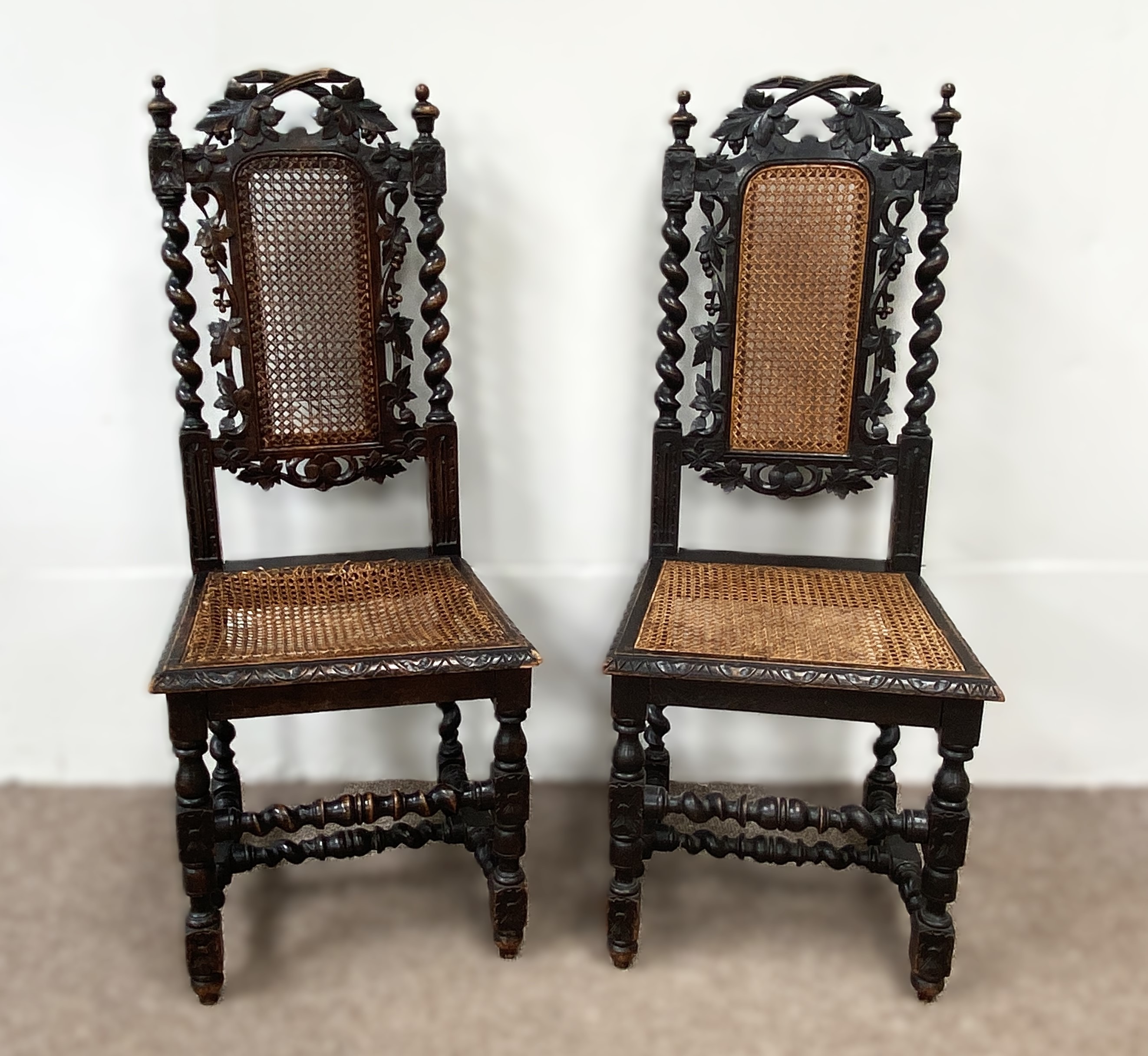 A pair of late Victorian oak framed hall chairs, with vine carved crests and caned seats; also two