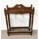 A late Victorian oak stick stand, circa 1900, with a 'Swan Neck' moulded crest rail and turned