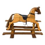 A modern child’s rocking horse, on a safety stand, with a carved hardwood and pine body, and leather