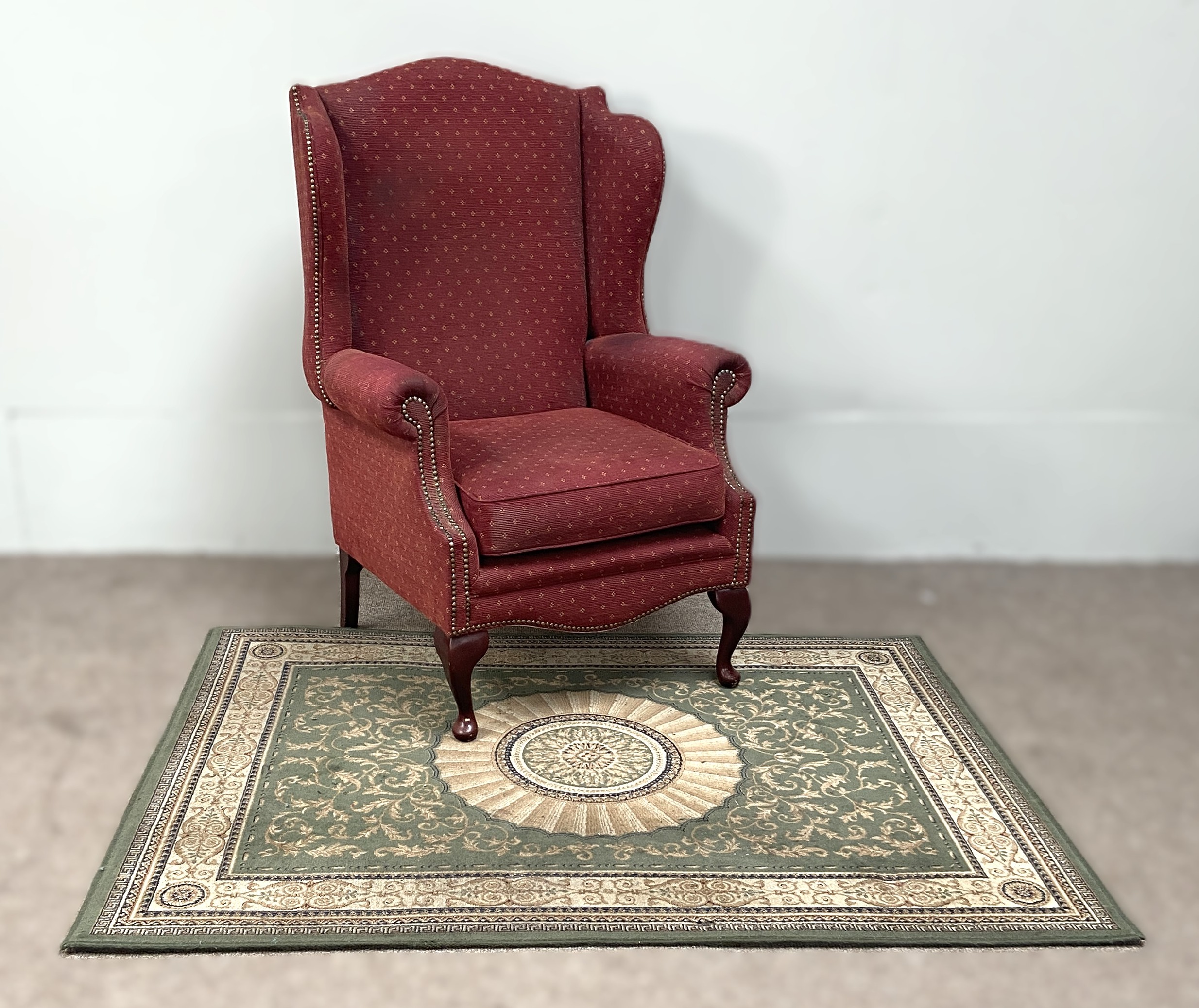 A vintage wing backed armchair, with claret upholstery; also a modern decorative rug (2)