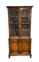 A mid 20th century oak bookcase, with two arched and glazed doors, opening to shelves, over two