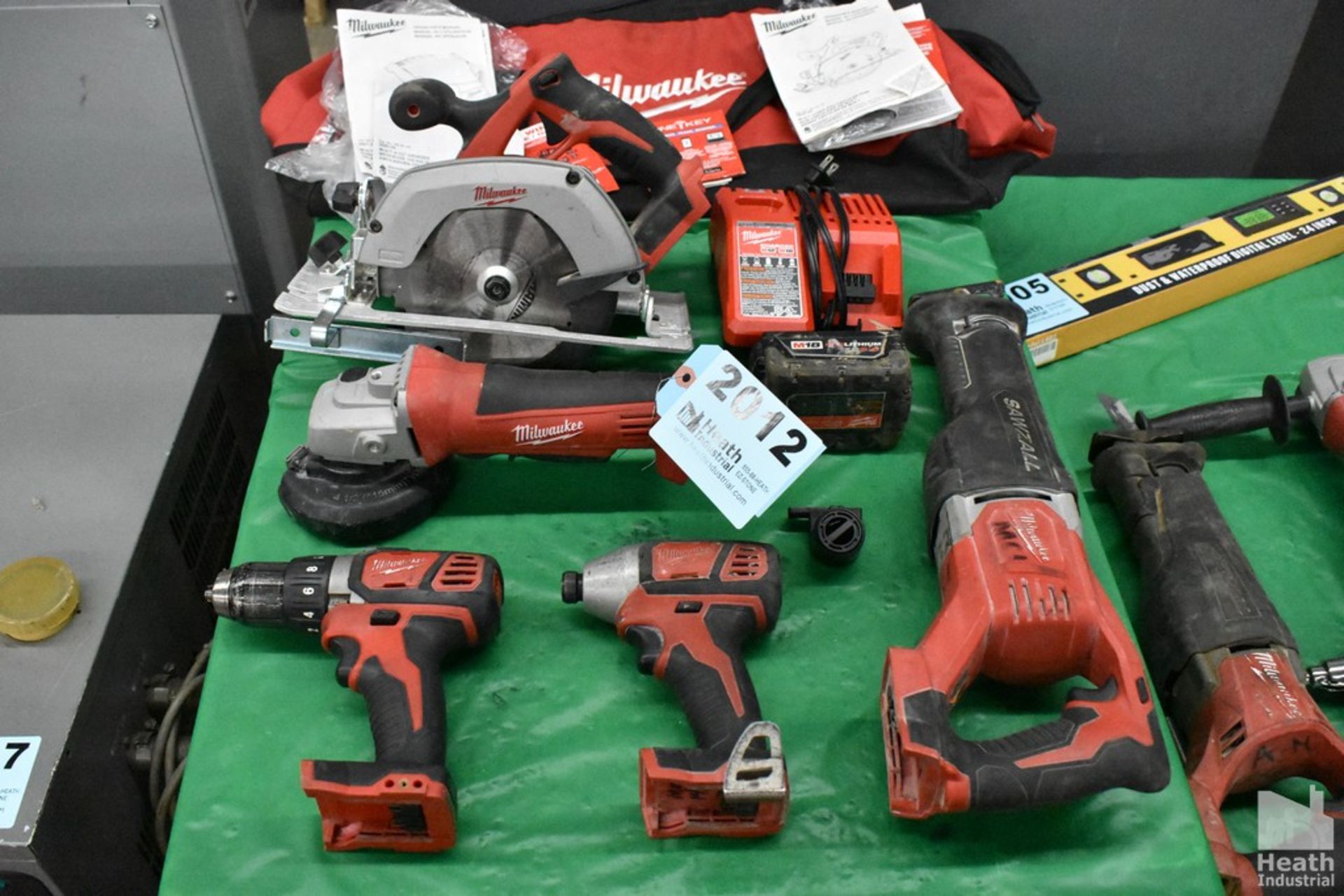 ASSORTED MILWAUKEE TOOLS ON TABLE, WITH CHARGER, BATTERY AND CARRYING BAG