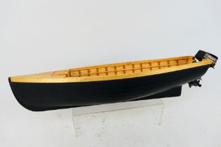 An unmarked wooden, kit built boat / dinghy with plastic outboard with outboard motor.