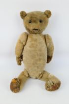 An early 20th century jointed arm bear with ebonised wood eyes, approximately 39 cm (l),