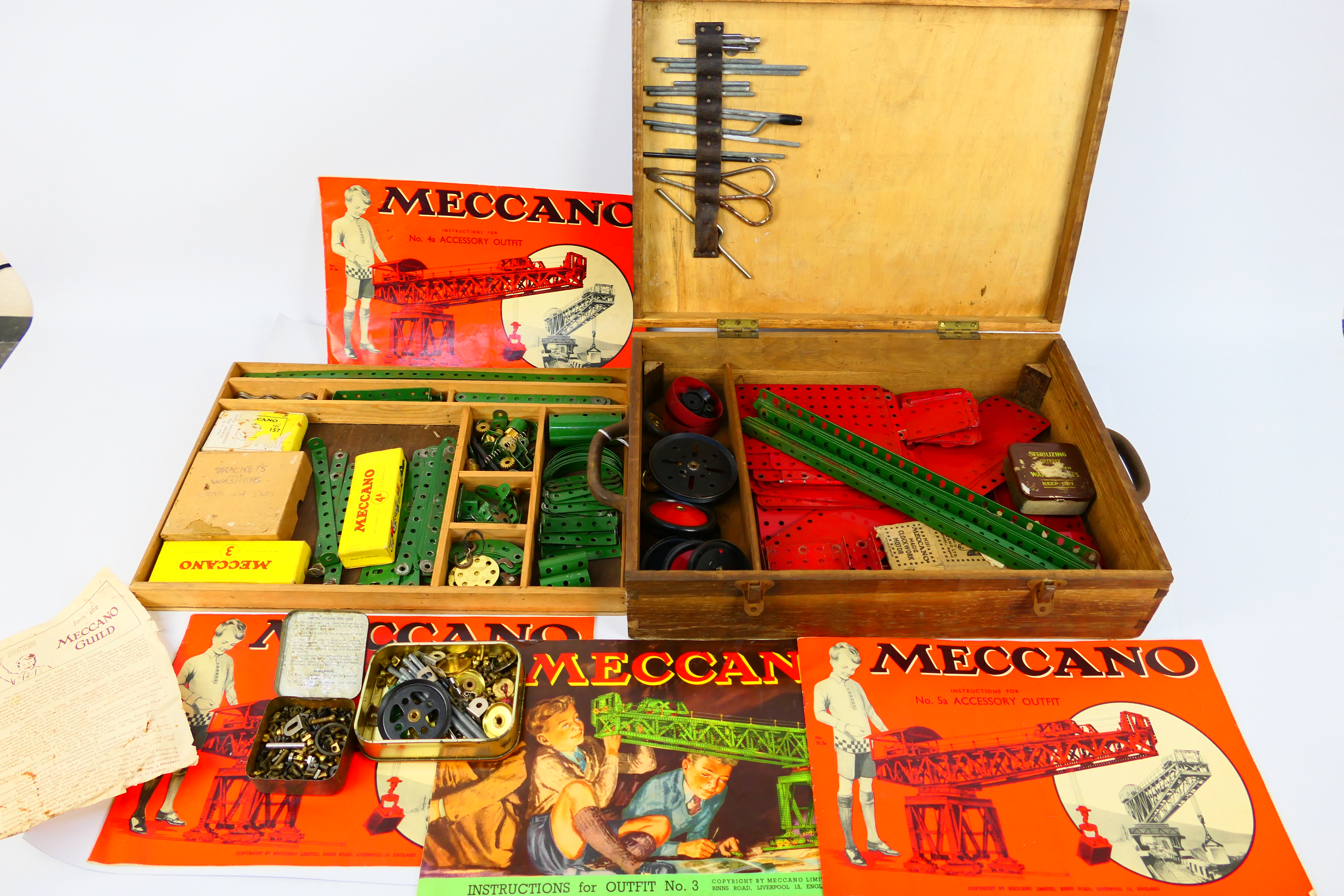 Meccano - A vintage wooden boxed Meccano set containing a quantity of red and green parts, wheels,