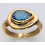 An 18K Yellow Gold Blue Gemstone (possibly topaz) Ring. Pear shaped stone set within a raised