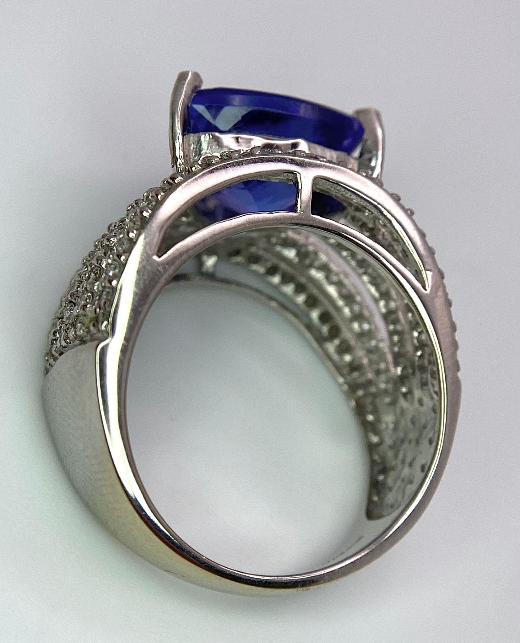 An 18K White Gold, Tanzanite and Diamond Ring. Trillion cut tanzanite with a five row diamond arch - Image 9 of 11