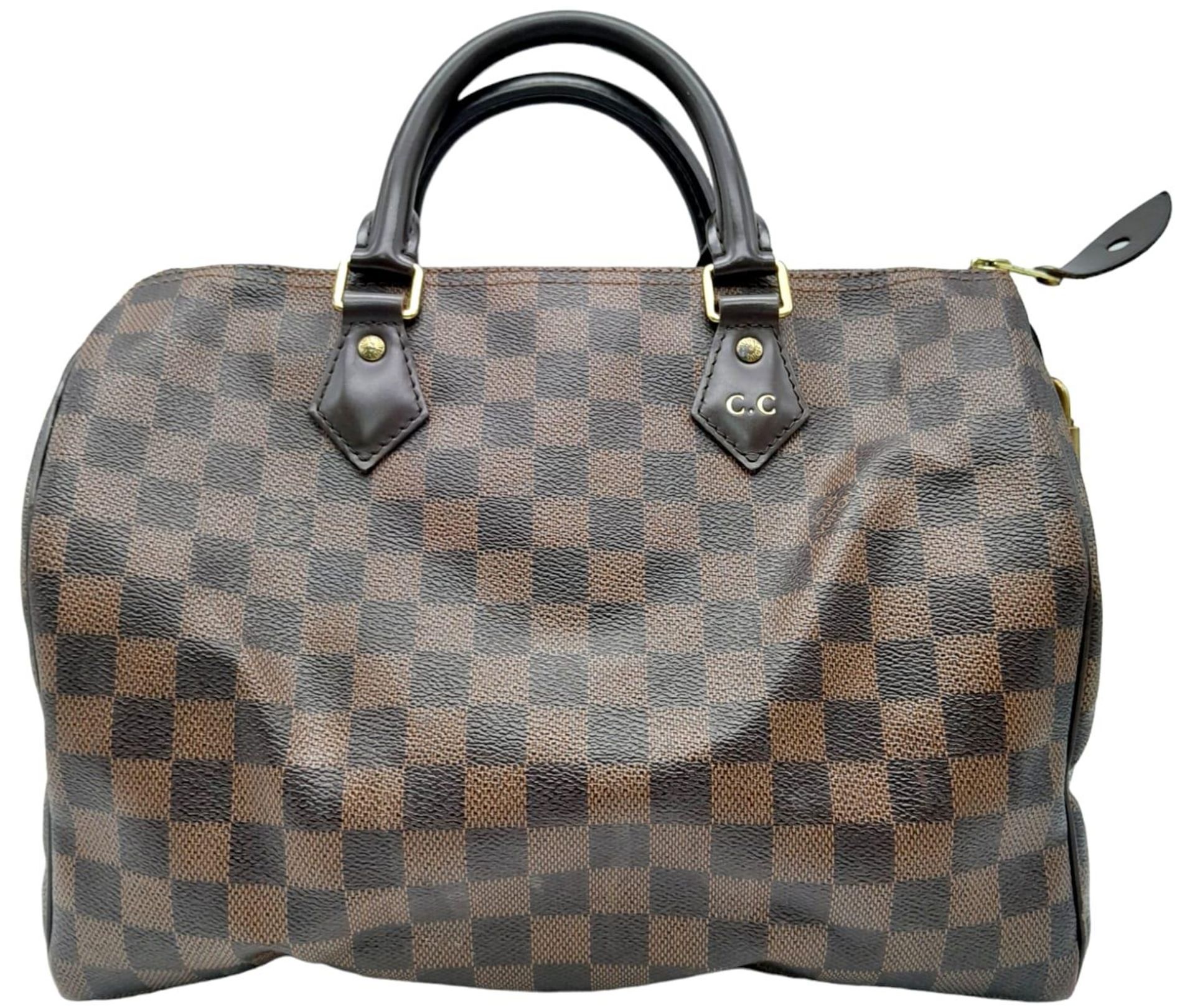 A Louis Vuitton Speedy Bag. Checked LV canvas exterior. Red textile interior. Comes with dust cover,
