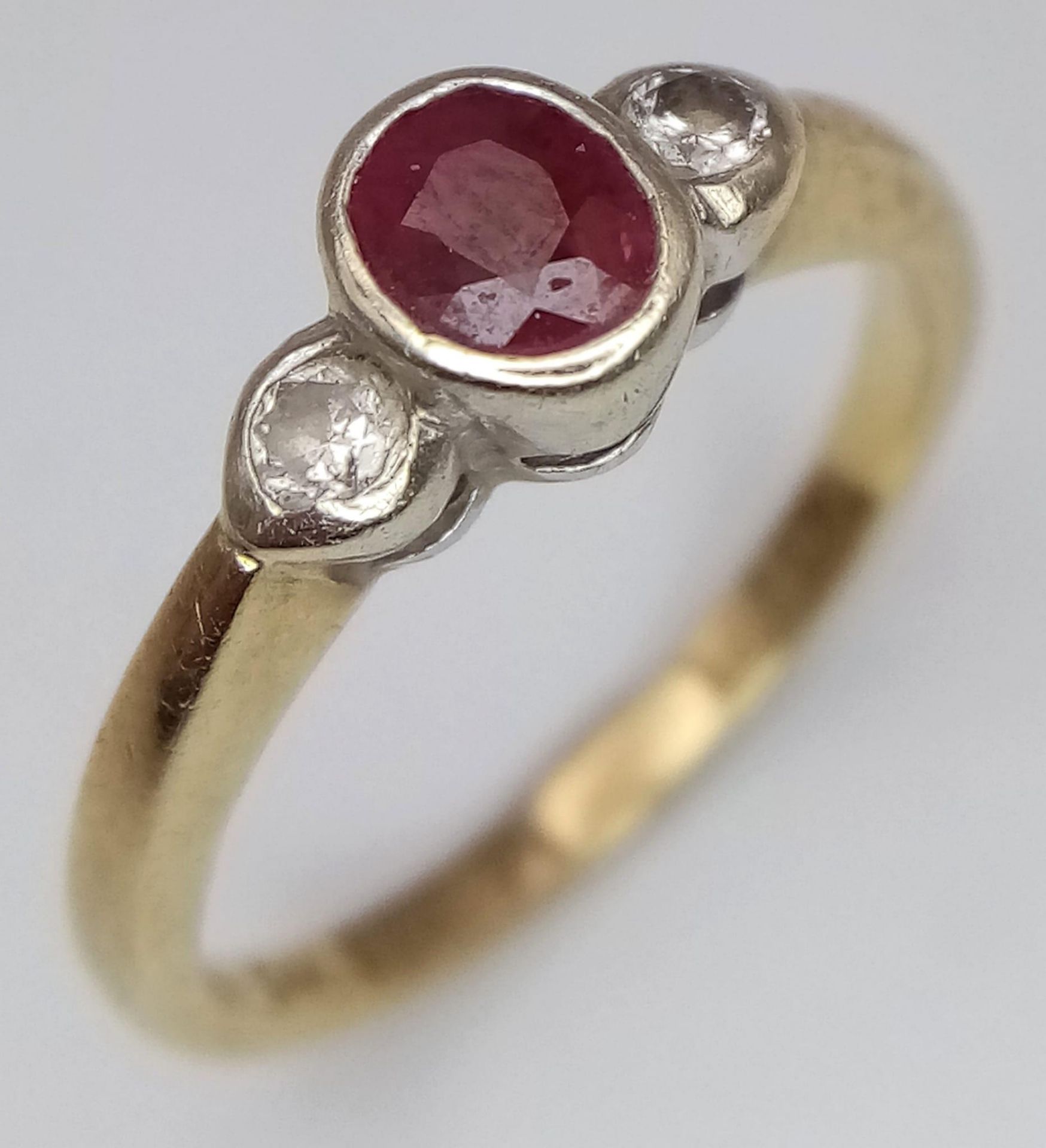 A 9 K yellow gold ring with an oval cut ruby and two round cut diamonds (0.10 carats), ring size: