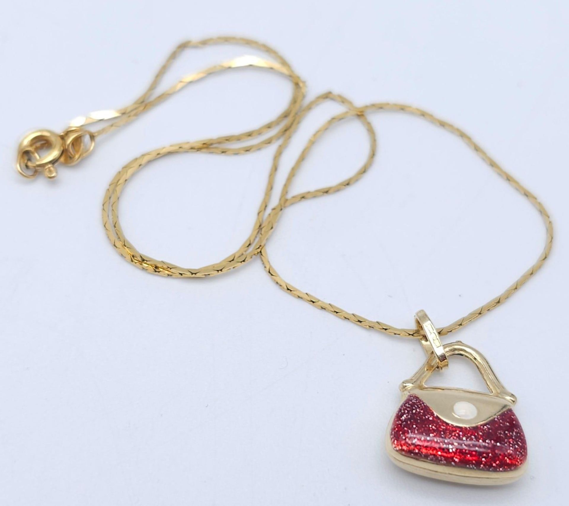 An Italian 14k Yellow Gold Pendant in the Shape of a Handbag with Red Glitter Enamel Detailing on