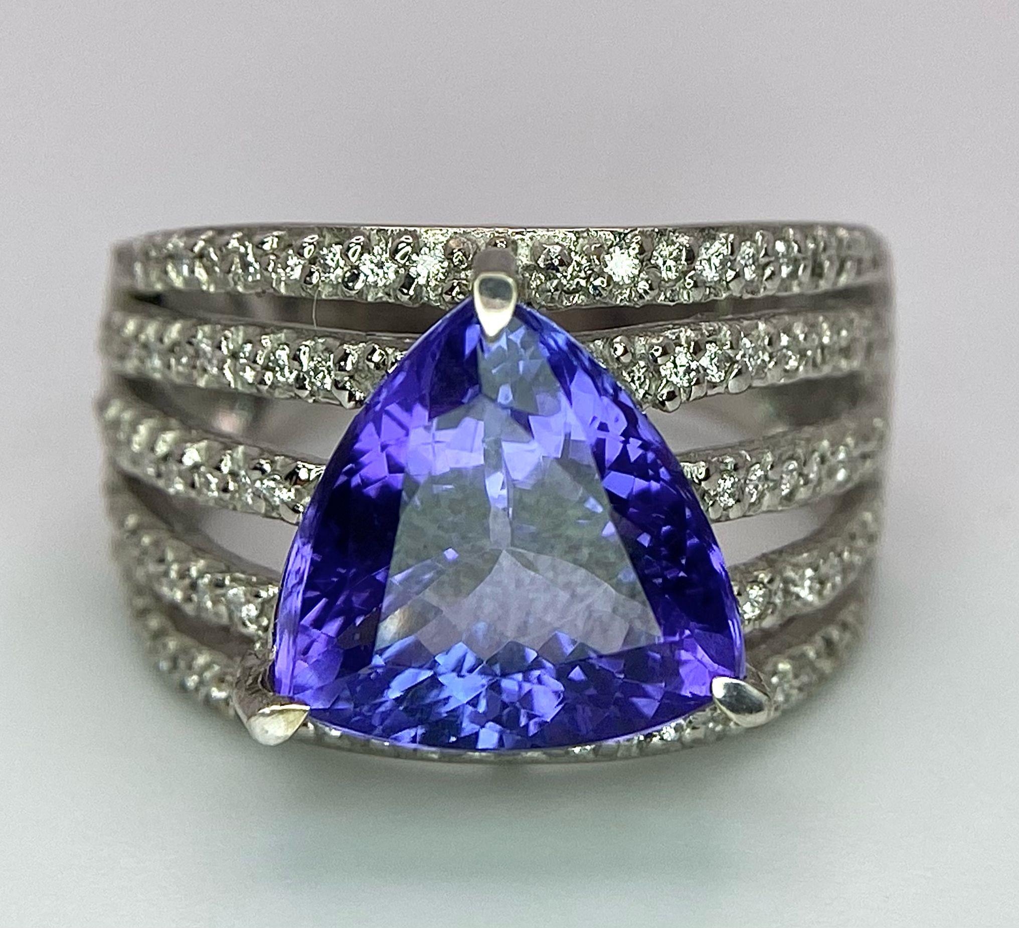 An 18K White Gold, Tanzanite and Diamond Ring. Trillion cut tanzanite with a five row diamond arch - Image 6 of 11