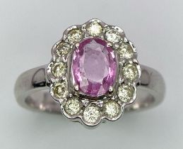 A 9K White Gold, Diamond and Pink Sapphire Ring. Central oval cut pink sapphire with a diamond halo.