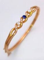 A 15K Yellow Gold, Diamond and Sapphire Bangle. A central round cut sapphire with a brilliant