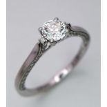 An 18K White Gold and Diamond Ring. A central brilliant round cut diamond with diamond accents on