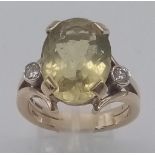 A 9K Yellow Gold Citrine and Diamond Ring. Large central oval citrine with a round cut diamond