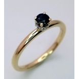 A 9 K yellow gold ring with a single sapphire, standing proud, with a halo of diamonds on its