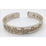 A Tibetan silver bangle with Tibetan language characters on the outside and Chinese language