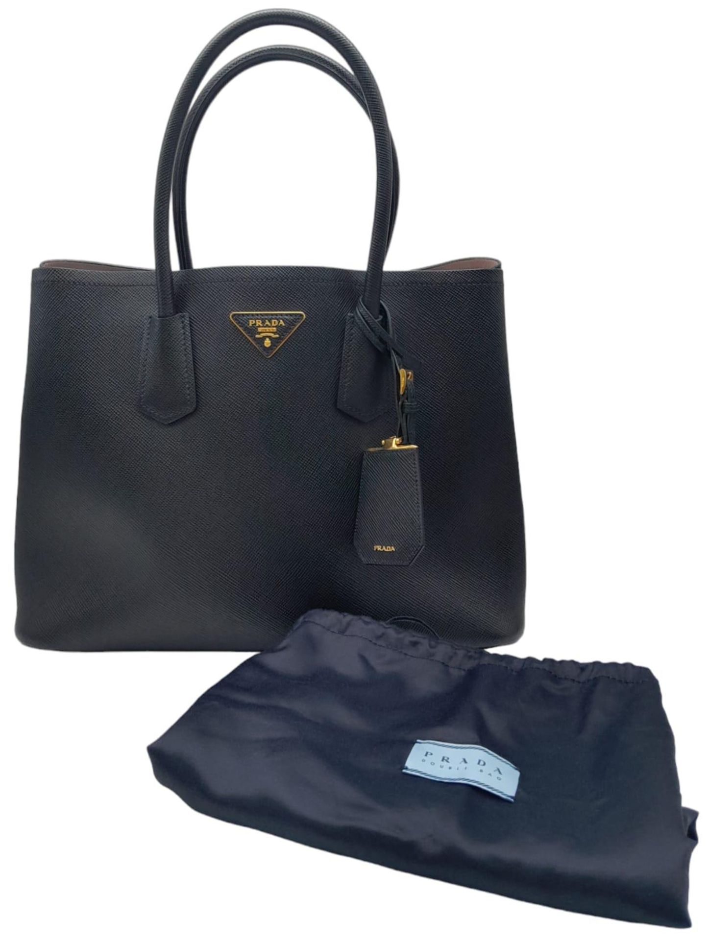 A Prada Black Leather Handbag. Textured black exterior with gold-tone hardware. Pastel pink