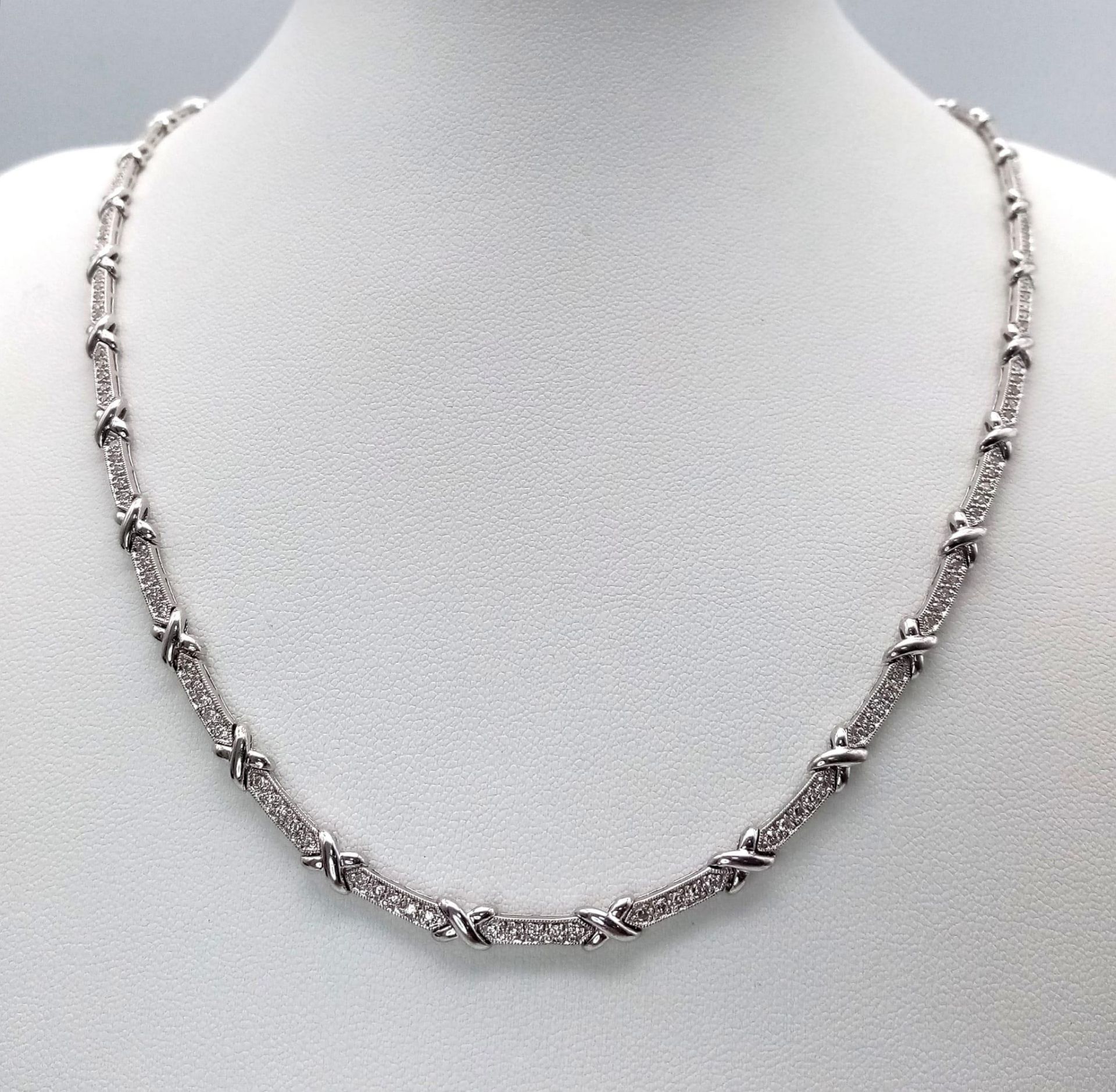 An 18K White Gold and Diamond Bar Link Necklace. 1.24ctw of diamonds. Love-knot separators. 43cm