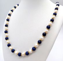 A Lapis Lazuli and Cultured Pearl Long Necklace. Gilded spacers and clasp. 70cm length.