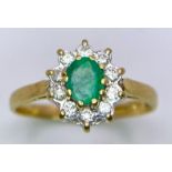 An 18 K yellow gold rind with an oval cut emerald surrounded by a halo of diamonds. Ring size: M,