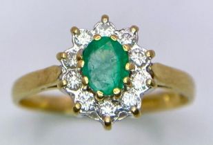 An 18 K yellow gold rind with an oval cut emerald surrounded by a halo of diamonds. Ring size: M,