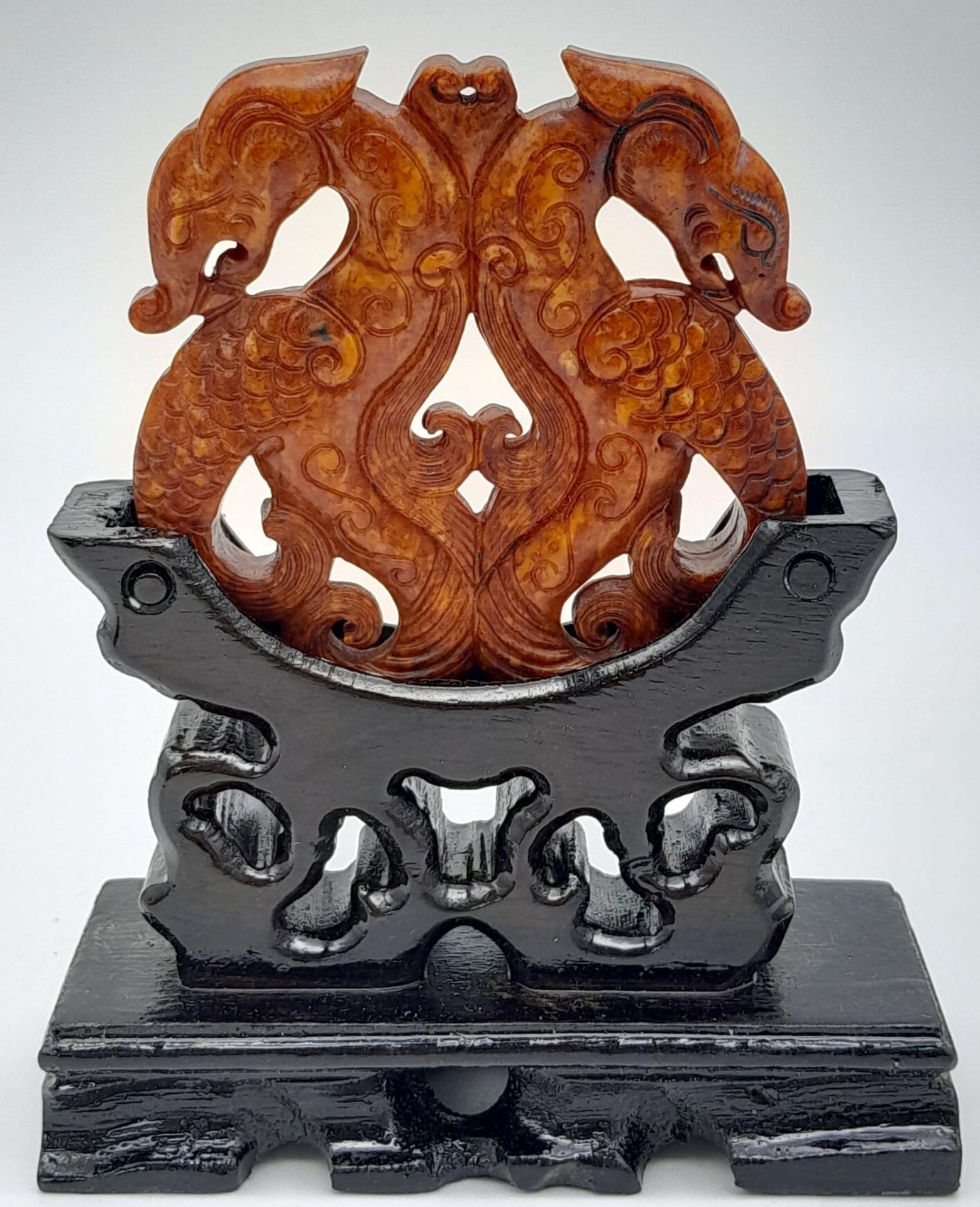 A Chinese carved reddish brown jade amulet with a fascinating, highly detailed design of two