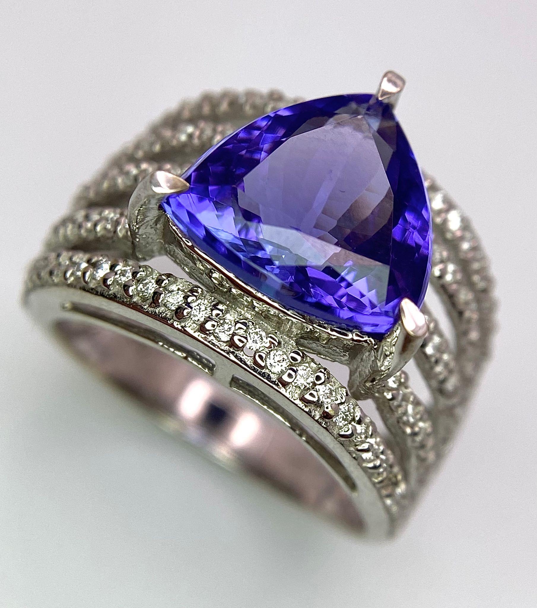 An 18K White Gold, Tanzanite and Diamond Ring. Trillion cut tanzanite with a five row diamond arch - Image 5 of 11