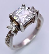 A 925 Silver Ring with large central White Stone, flanked on the shoulders with smaller stones.