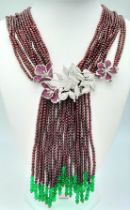 A statement necklace consisting of eleven strands of round garnets with a spectacular central floral